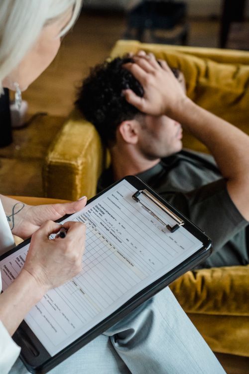 Therapist writing on clipboard during a CBT therapy session with a patient